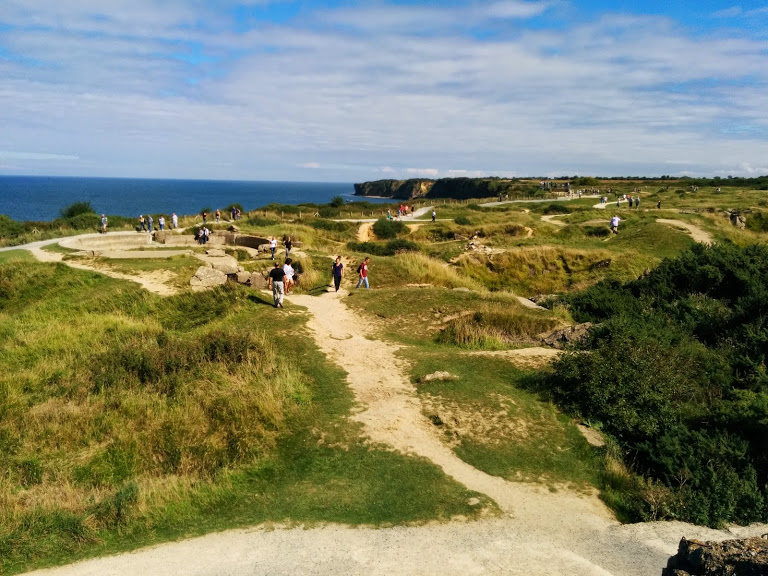 Path going through the demolished bunkers and craters of Pointe du Hoc. The edge of the cliff on the left hand side