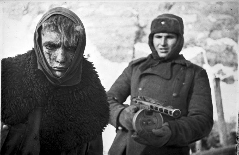 Battered and bleeding German prisoner escorted by a proud Soviet soldier